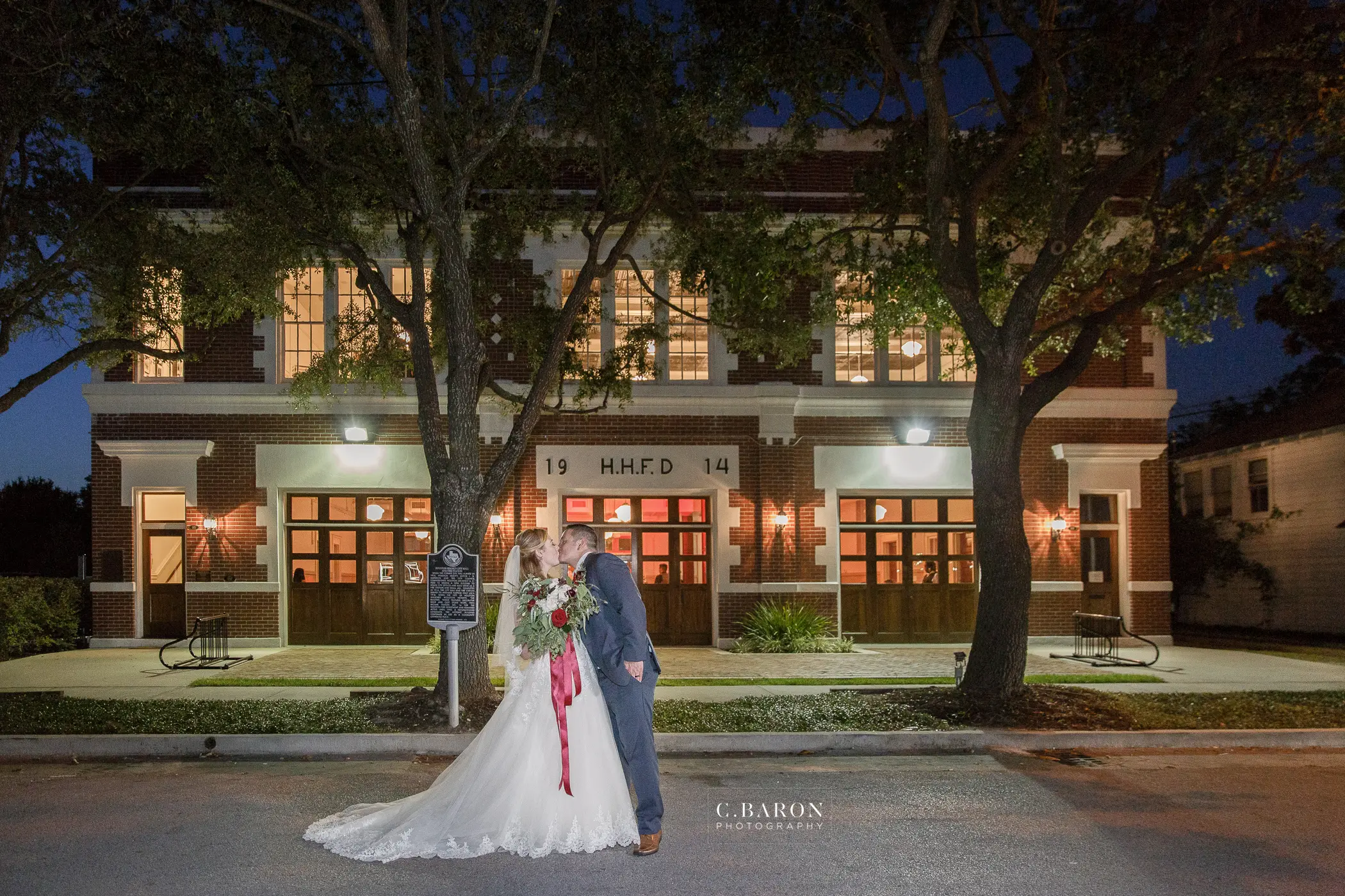 A bride and groom in front of the historic Heights Fire Station at dusk