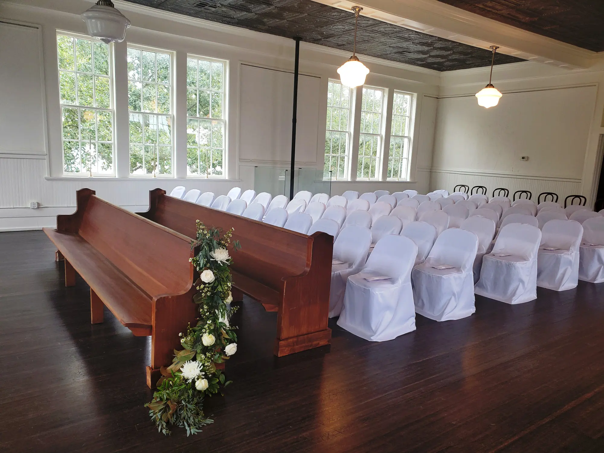 Wooden pews and white chairs set for a ceremony on the second floor